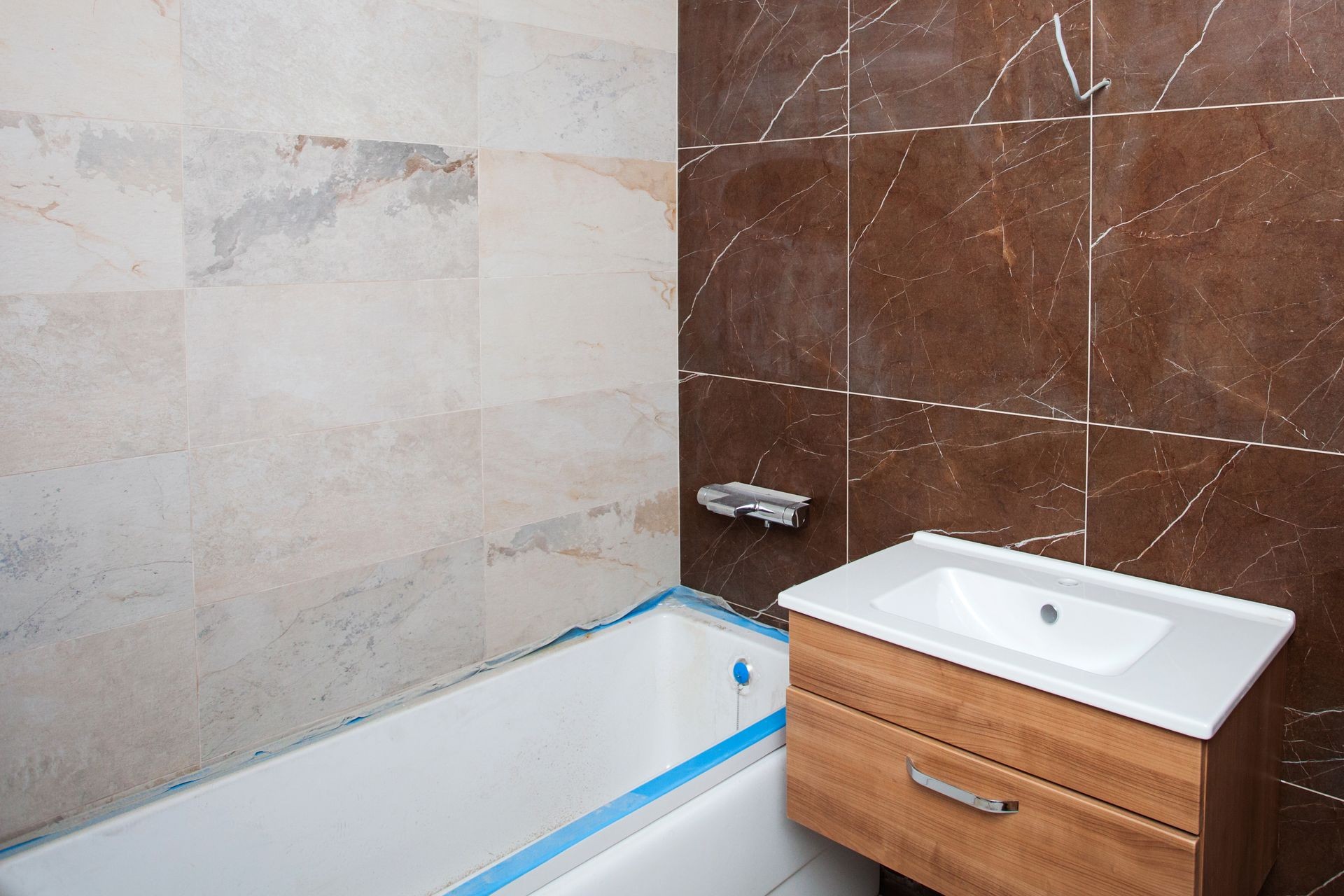 Unfinished Interior of repair and renovation bathroom.  A bathroom remodeling project and design wetroom. Brown marble on the walls. Furniture in protective film.